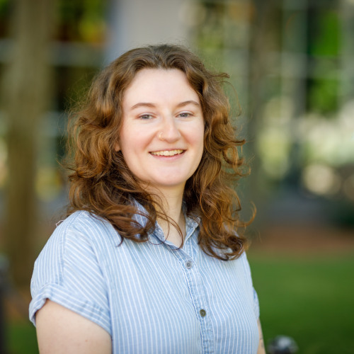 Zoe Goldenberg-Hart smiles at the camera in front of the School of Public Health 
